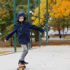 小城市男孩与一个便士滑板。孩子在 autu 滑冰