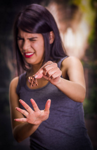 美丽而孤独的女孩患有小儿厌食症，她手里拿着一块巧克力和另一只手，在模糊的背景做的与她停止标志