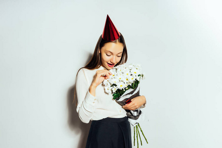 年轻快乐的女孩，在节日帽，手里拿着一束白色的鲜花