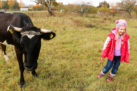 美丽的小女孩站在草地附近的黑牛链