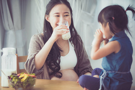 亚洲家庭幸福妈妈和女儿喝牛奶照片