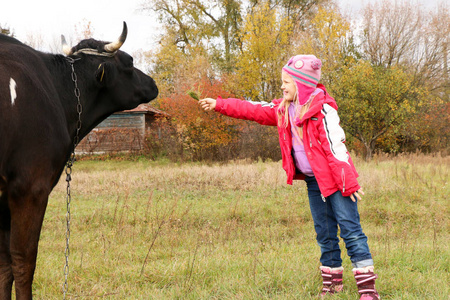美丽的小女孩站在草地附近的黑牛链