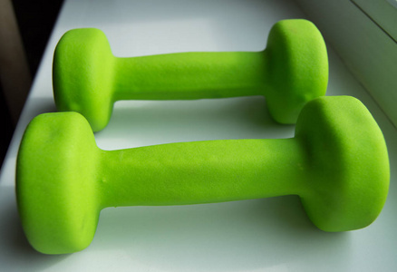 健身，健康的生活方式   两个绿色哑铃体育的概念