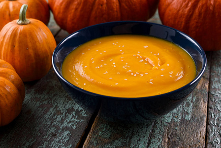 盘子里的橙色南瓜汤,汤匙蔬菜汤,饼干在蓝色碗自制素食南瓜汤装饰着