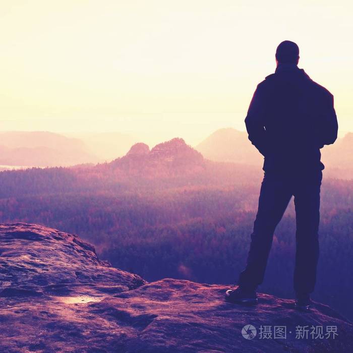 年轻的自信和强大男人站两手叉腰晚一天太阳的轮廓