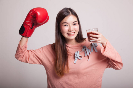 年轻的亚裔女子和番茄汁和拳击手套