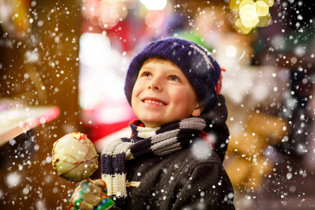 小小孩男孩吃糖苹果糖果站在圣诞市场