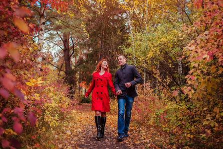 对年轻的夫妇在秋天的树林，多彩的树林中运行