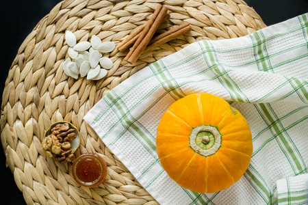小南瓜种子，小小的玻璃可以蜂蜜 核桃和肉桂棒上圆垫餐巾的凤眼莲在黑色的背景和绿白色格仔华夫格毛巾