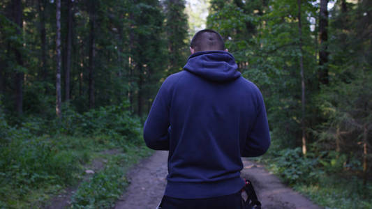 年轻人在树林里戴一顶帽子。运动员走进森林里去做运动