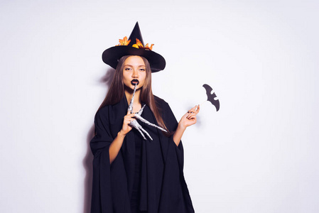 年轻性感的哥特式女孩形象的女巫在万圣节那天,在大的黑色帽子,装饰着