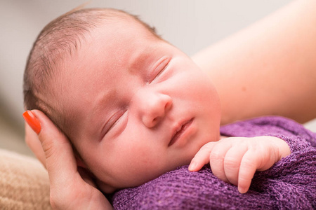 紫罗兰在熟睡的刚出生的婴儿女孩编织婴儿毯