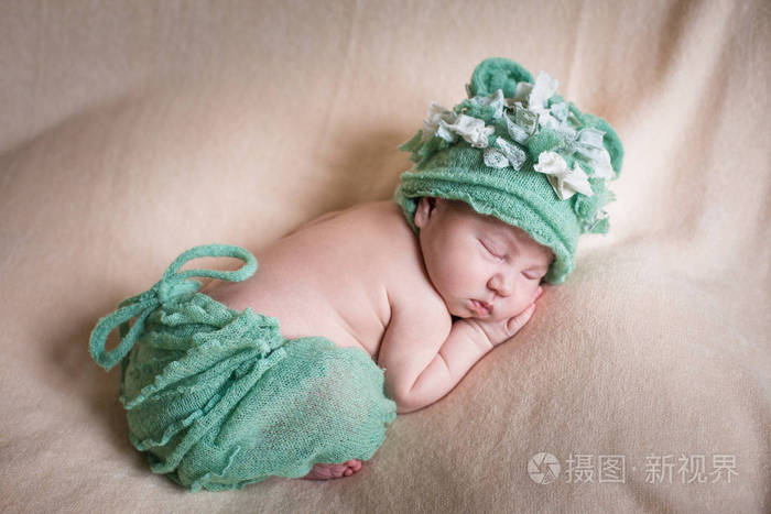 熟睡的刚出生的婴儿女孩绿色针织内裤及帽子