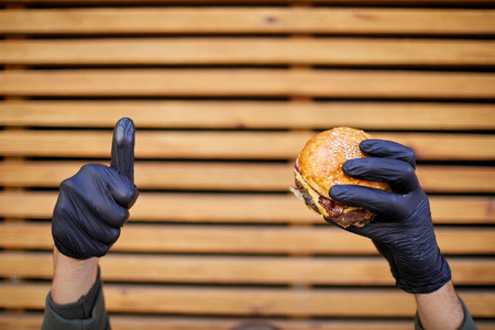 Juisy 汉堡与牛肉在男性手上的木质背景。食品概念
