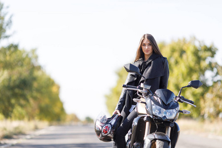 女孩坐在一辆摩托车在黑色皮革服装