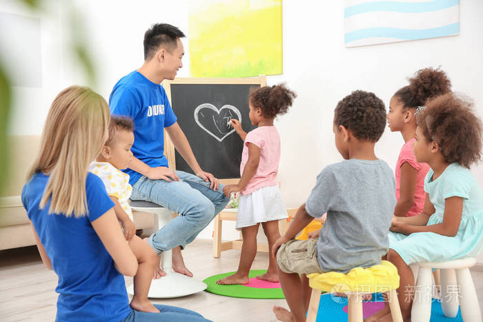 年轻的志愿者们在灯光室里和小孩玩耍.国外志愿服务概念