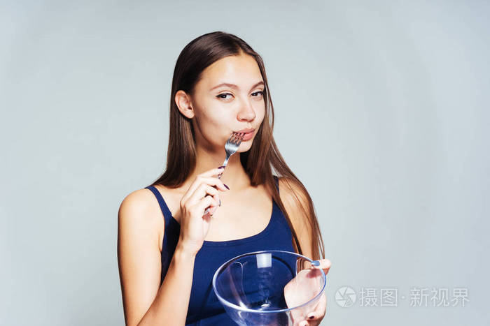 快乐的女孩嚼东西拿着空碗