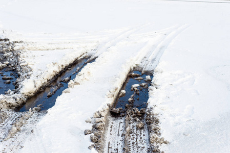 在路上，轮胎轨道与水坑泥在融化的雪纹理的冬天