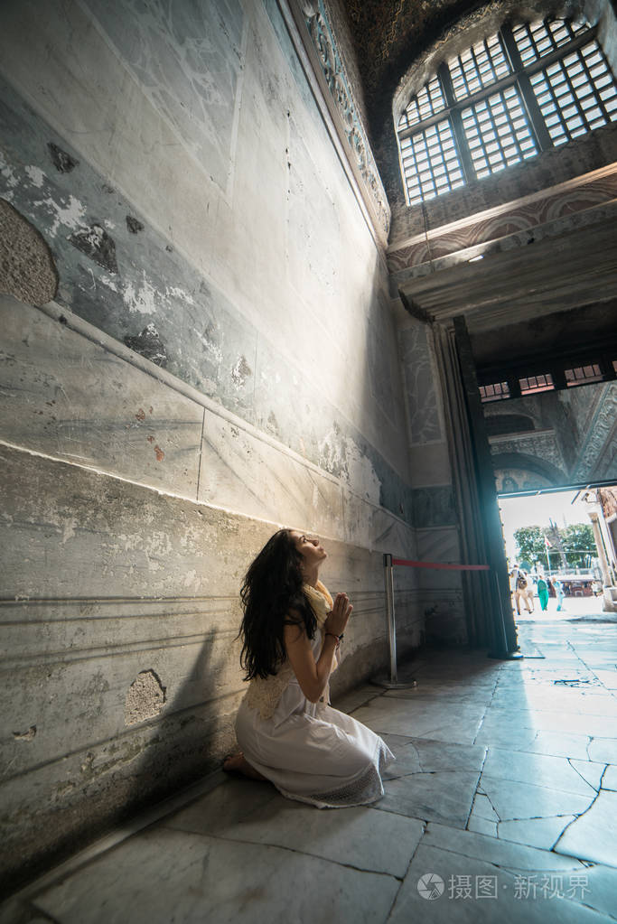 悲伤,失去了希望,女孩在寺跪在神圣的光芒祈祷