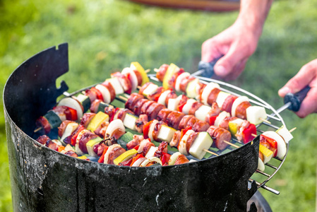 对烤肉串烧烤在花园里，男人准备肉串配蔬菜和肉，烧烤食物，夏天花园里的户外聚会