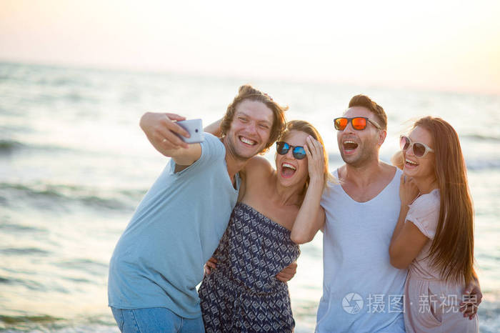 一群快乐的年轻人在海滩上拍照