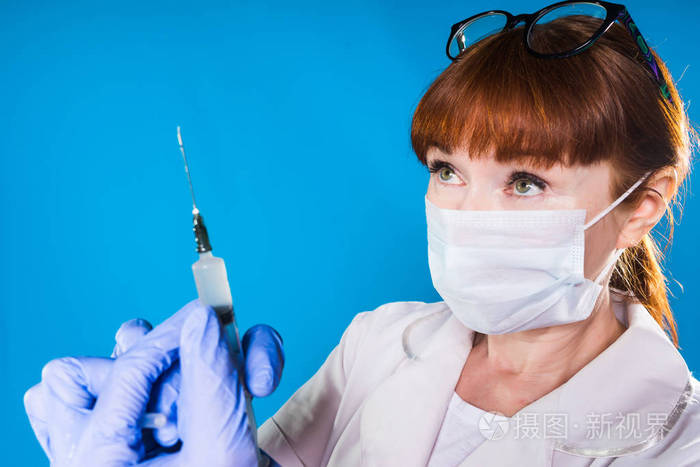 戴着面具的红发护士持有一个注射器在她的手,孤立