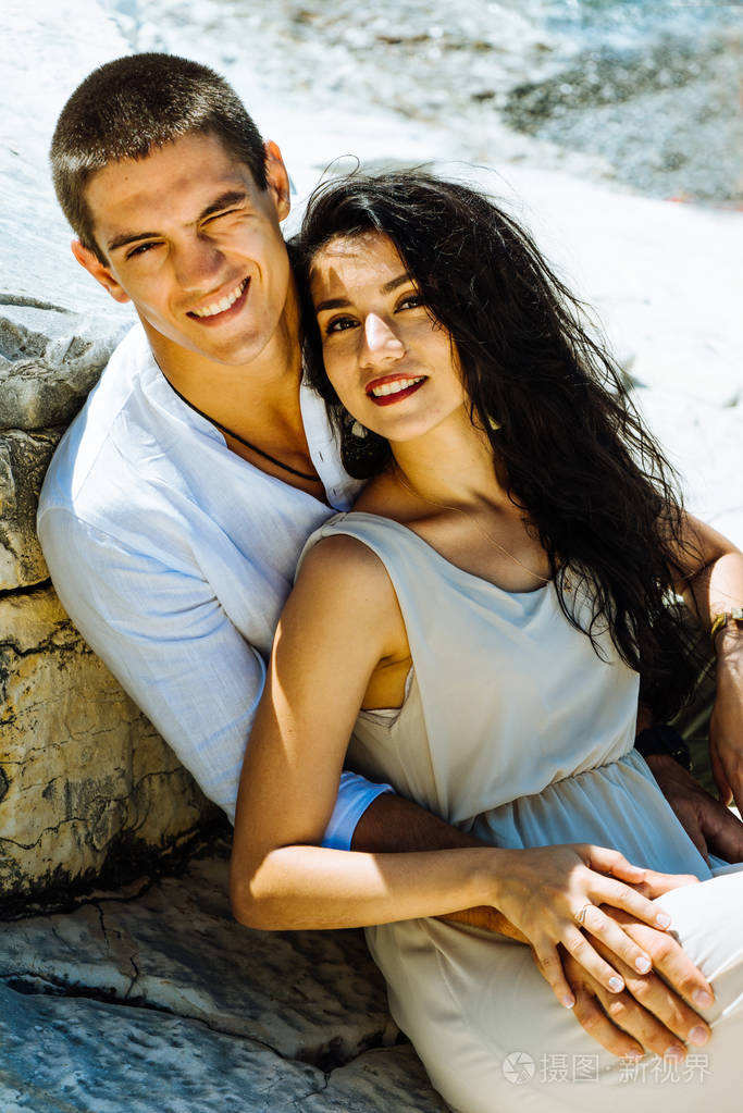 爱看看相机和拥抱的年轻快乐的夫妇在眼中闪耀的太阳