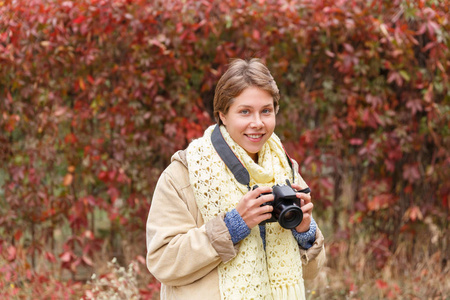 在一个秋天的树林，带着照相机的年轻女孩