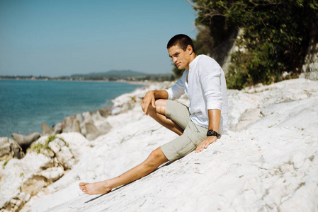 时尚的家伙，在明亮的夏天的衣服和海边的白色岩石上构成一个时钟