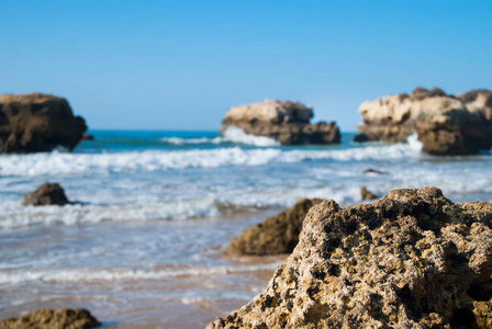 野生的夏天的海滩，葡萄牙。晴朗的天空，在沙子上的岩石