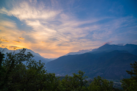 在日落时意大利的阿尔卑斯山。夏天五颜六色上空雄伟的山峰 林地和绿色的山谷