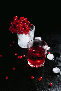 两个冷冻的眼镜与一个红色的鸡尾酒和冰，与琼花在一个黑色的湿背景和飞溅