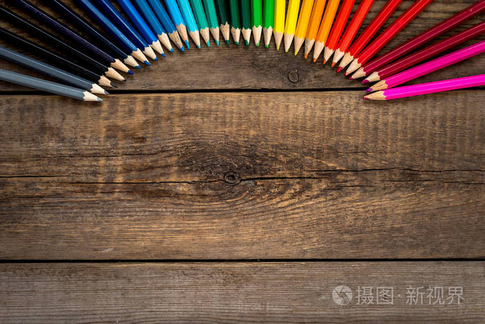 彩色的铅笔在梯度顺序位于折叠上木桌。学校的概念。复制空间