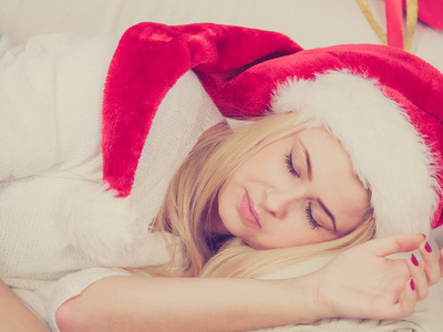 圣诞老人的帽子在沙发上睡觉的女人