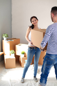 快乐的年轻夫妇开箱或填料盒和搬入新屋。对年轻的夫妇