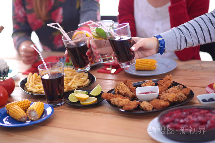 顶视图的一群人在一起时坐在木桌吃饭。在桌子上的食物。人们吃快餐