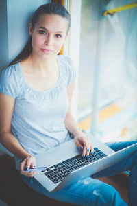 年轻漂亮的女人在家里使用一台笔记本电脑。年轻漂亮的女人