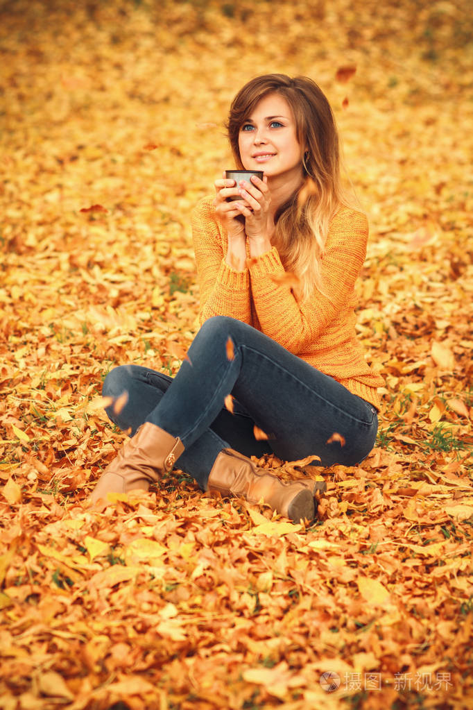 积极的女孩,穿着牛仔裤和毛衣自然下降中的黄色树叶秋天肖像