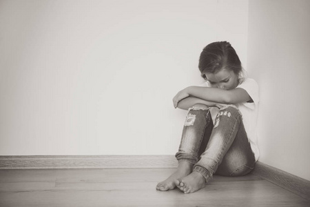 小哀伤的女孩坐在地板在家