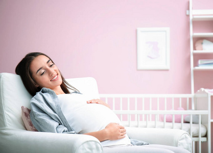 怀孕的女人坐在宝宝的房间里