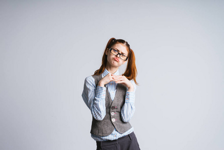 滑稽的女孩与两个马尾辫,戴着眼镜使她的脸,看着镜头,孤立照片