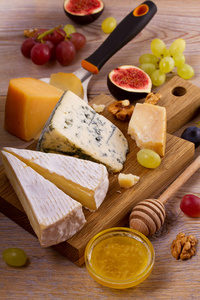 奶酪板。各种类型的奶酪与葡萄 蜂蜜 无花果和仿古的木桌上的螺母