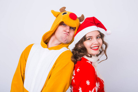 幸福的年轻女人在圣诞老人的帽子和嘉年华服装的鹿的人。乐趣 假日 笑话和圣诞节的概念