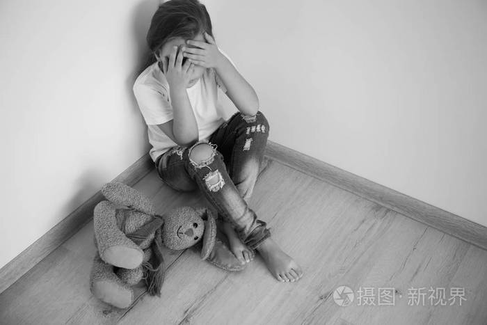 害怕的小女孩坐在房间的角落里概念