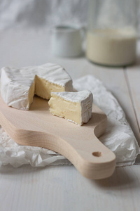 在白色的木桌上切片新鲜的乳酪奶酪。选择性焦点