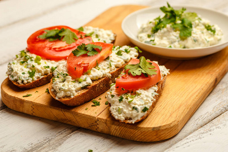 三明治加健康黑麦面包 奶油奶酪 西红柿白色木制的桌子上。对一种健康食物的爱
