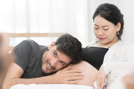 丈夫正在听他怀孕的妻子肚皮