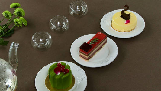 漂亮的透明茶壶水壶与美味绿色红茶与苹果, 蜡烛和甜点在背景中.