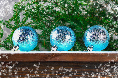 三蓝色新年球躺在一个木质的棕色架子上, 四周是冷杉树枝