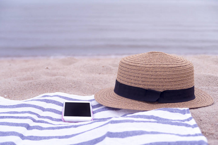 帽子和智能手机在海滩上